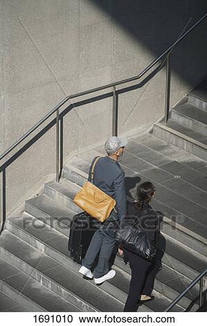 Full length of business colleagues walking with bag on steps View Large Photo Image Stock Image - Full length of business colleagues walking with bag on steps. Fotosearch