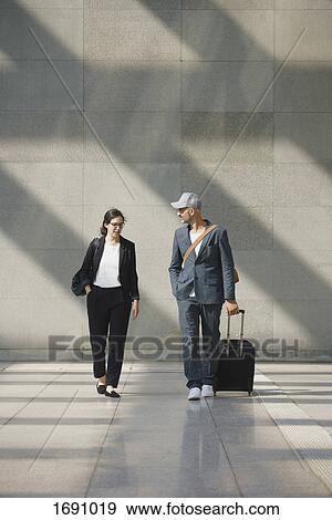 Full length of confident business people with wheeled luggage walking at airport View Large Photo Image Stock Photo - Full length of confident business people with wheeled luggage walking at airport. Fotosearch