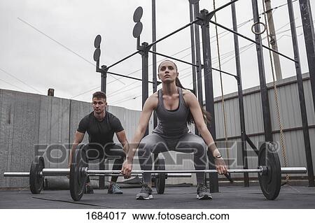 Full length of determined male and female athlete exercising with barbells during crossfit training View Large Photo Image Stock Photo - Full length of determined male and female athlete exercising with barbells during crossfit training. Fotosearch