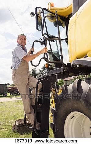 Full length of man climbing on agricultural machinery at farm against sky View Large Photo Image Stock Photo - Full length of man climbing on agricultural machinery at farm against sky. Fotosearch