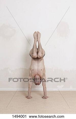 Full length of man doing handstand while performing yoga View Large Photo Image Stock Image - Full length of man doing handstand while performing yoga. Fotosearch