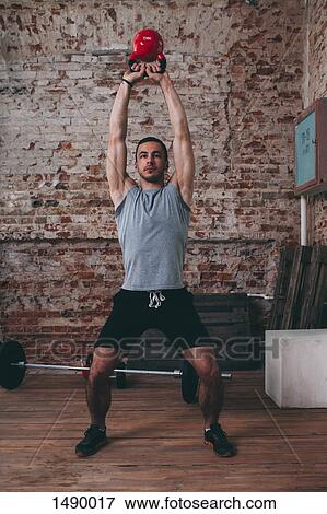 Full length of man lifting kettlebell at gym View Large Photo Image Stock Photo - Full length of man lifting kettlebell at gym. Fotosearch