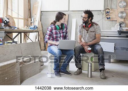 Full length of mid adult carpenters discussing while using laptop in workshop View Large Photo Image Stock Photo - Full length of mid adult carpenters discussing while using laptop in workshop. Fotosearch