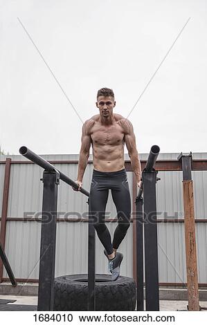 Full length of shirtless muscular male athlete exercising on parallel bars View Large Photo Image Stock Image - Full length of shirtless muscular male athlete exercising on parallel bars. Fotosearch