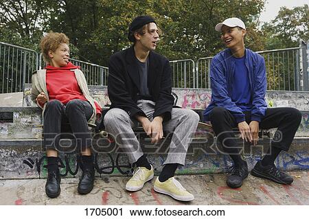 Full length of smiling friends talking while sitting on steps at park View Large Photo Image Stock Image - Full length of smiling friends talking while sitting on steps at park. Fotosearch