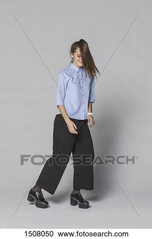 Full length of smiling woman with tousled hair standing against gray background View Large Photo Image Stock Image - Full length of smiling woman with tousled hair standing against gray background. Fotosearch