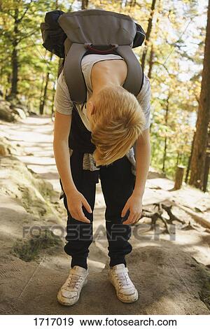 Full length of tired boy with backpack bending against trees in forest View Large Photo Image Stock Photo - Full length of tired boy with backpack bending against trees in forest. Fotosearch