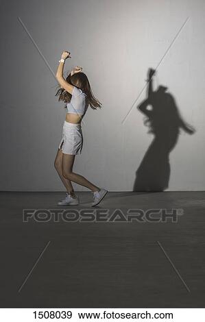 Stock Photo - Full length of woman dancing against gray background. Fotosearch