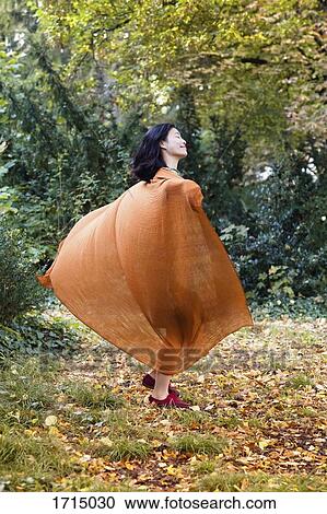 Full length of woman wearing orange scarf dancing against trees at park View Large Photo Image Stock Image - Full length of woman wearing orange scarf dancing against trees at park. Fotosearch