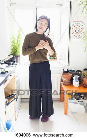 Full length of young woman with hands clasped standing against window in kitchen View Large Photo Image Stock Photograph - Full length of young woman with hands clasped standing against window in kitchen. Fotosearch