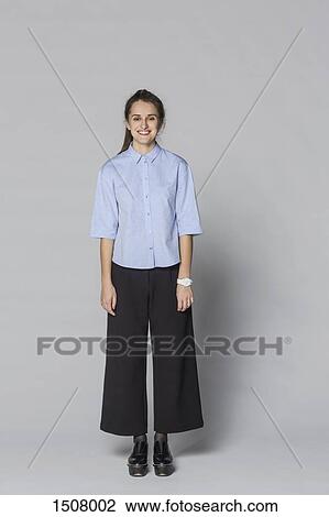 Full length portrait of smiling woman standing against gray background View Large Photo Image Stock Image - Full length portrait of smiling woman standing against gray background. Fotosearch