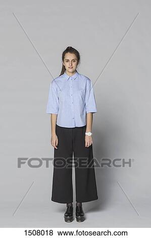 Full length portrait of smiling woman standing against gray background View Large Photo Image Stock Photo - Full length portrait of smiling woman standing against gray background. Fotosearch