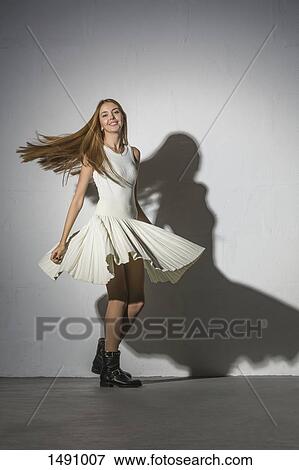 Stock Photo - Full length portrait of woman spinning against white background. Fotosearch