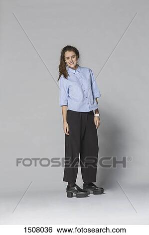 Full length smiling woman standing against gray background View Large Photo Image Stock Photograph - Full length smiling woman standing against gray background. Fotosearch