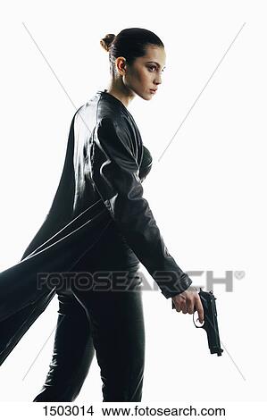 Picture - Furious spy holding gun walking against white background. Fotosearch