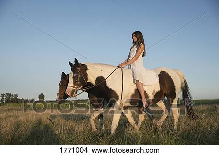 Picture - Girl bareback riding horse in rural field. Fotosearch