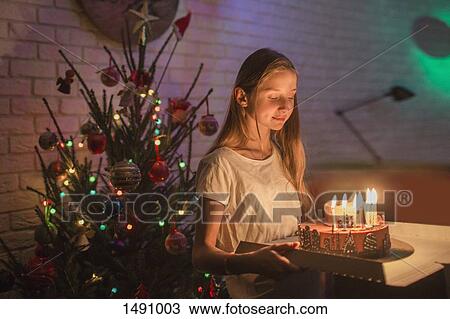 Girl carrying cake with candles in front of Christmas tree View Large Photo Image Stock Image - Girl carrying cake with candles in front of Christmas tree. Fotosearch