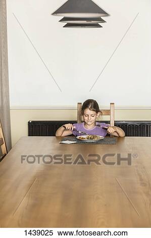 Girl having food at dining table in house View Large Photo Image Stock Photography - Girl having food at dining table in house. Fotosearch