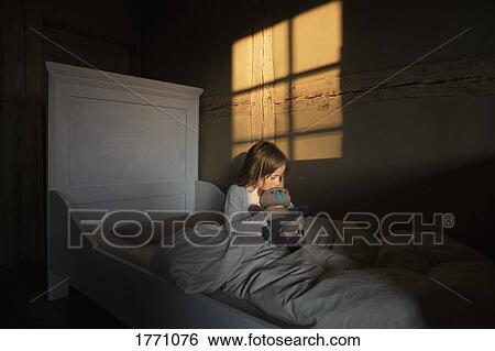 Stock Photograph - Girl hugging teddy bear in bed. Fotosearch