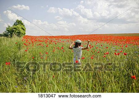 Stock Photo - Girl running in sunny, idyllic rural red poppy field. Fotosearch