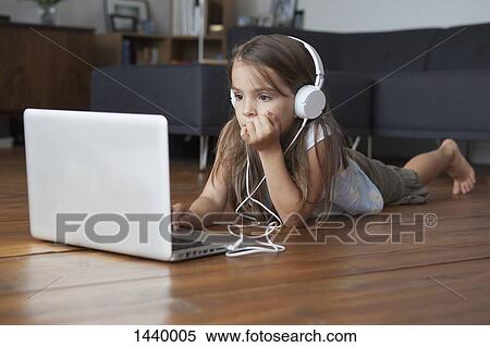 Girl using laptop while listening to music on hardwood floor View Large Photo Image Stock Photography - Girl using laptop while listening to music on hardwood floor. Fotosearch