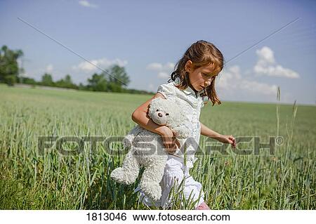 Girl with teddy bear walking in sunny, rural green field View Large Photo Image Stock Photograph - Girl with teddy bear walking in sunny, rural green field. Fotosearch