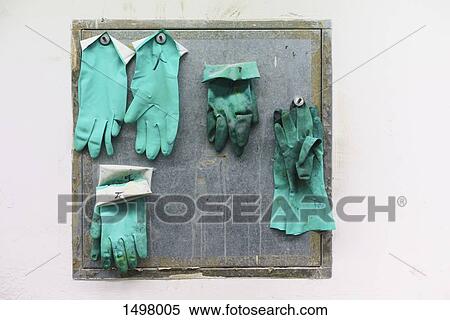 Stock Photography - Green gloves hanging on wall in factory. Fotosearch