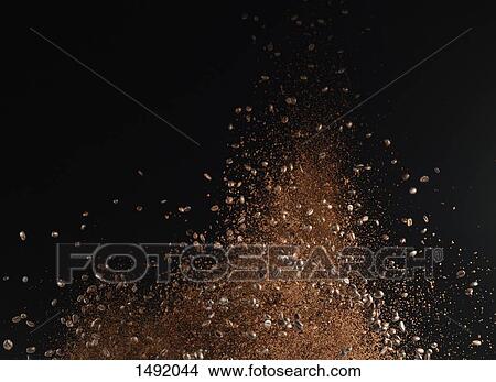Picture - Ground coffee beans in mid-air against black background. Fotosearch