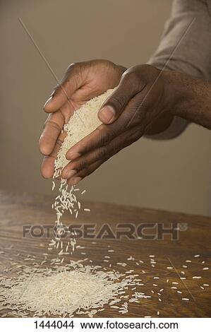 Hands pouring rice on table against colored background View Large Photo Image Picture - Hands pouring rice on table against colored background. Fotosearch