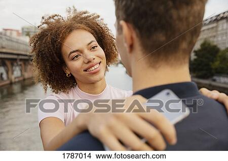 Picture - Happy, affectionate couple hugging on bridge. Fotosearch
