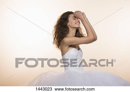 Stock Image - Happy bride standing against colored background. Fotosearch