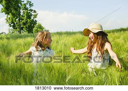 Happy, carefree sisters in sunny, idyllic rural green wheat field View Large Photo Image Stock Image - Happy, carefree sisters in sunny, idyllic rural green wheat field. Fotosearch
