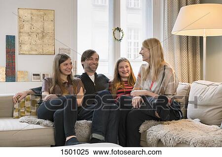 Happy family of four sitting together on sofa at home View Large Photo Image Stock Photography - Happy family of four sitting together on sofa at home. Fotosearch