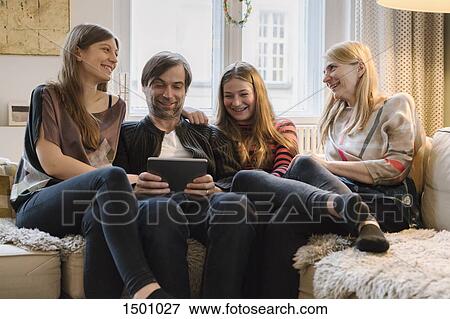 Stock Photo - Happy family with father using digital tablet in living room. Fotosearch