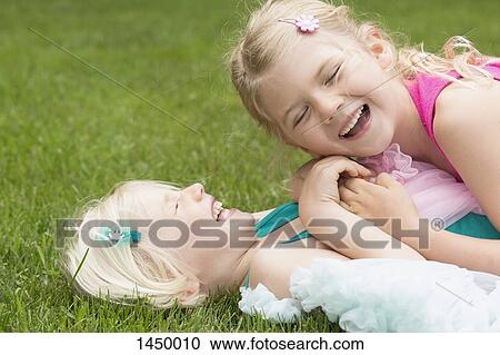 Happy girl lying on sister in backyard View Large Photo Image Stock Image - Happy girl lying on sister in backyard. Fotosearch