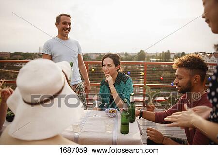 Happy male and female friends enjoying at outdoor table on patio against clear sky View Large Photo Image Stock Photo - Happy male and female friends enjoying at outdoor table on patio against clear sky. Fotosearch