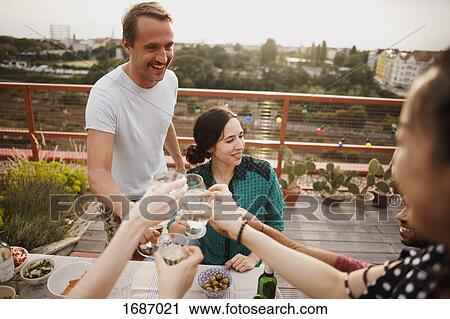 Happy male and female friends toasting wineglasses on patio View Large Photo Image Stock Image - Happy male and female friends toasting wineglasses on patio. Fotosearch