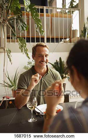 Happy man looking at woman while having food at dining table in house View Large Photo Image Stock Photography - Happy man looking at woman while having food at dining table in house. Fotosearch