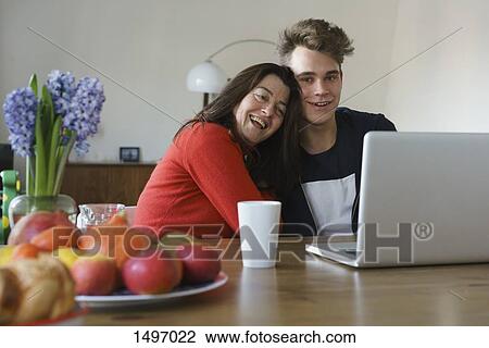 Happy mother and son sitting with laptop on table at home View Large Photo Image Stock Image - Happy mother and son sitting with laptop on table at home. Fotosearch
