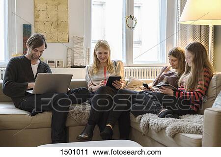 Happy parents with daughters using laptop and mobile devices in living room View Large Photo Image Stock Image - Happy parents with daughters using laptop and mobile devices in living room. Fotosearch