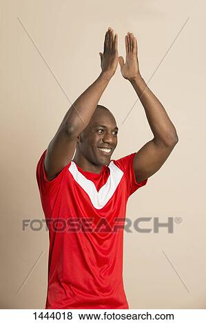 Happy soccer player applauding against colored background View Large Photo Image Stock Photo - Happy soccer player applauding against colored background. Fotosearch