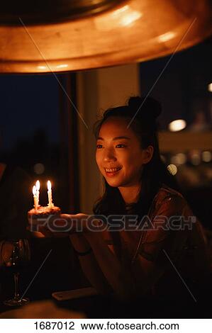 Happy woman holding small birthday cake with candles in darkroom View Large Photo Image Stock Image - Happy woman holding small birthday cake with candles in darkroom. Fotosearch