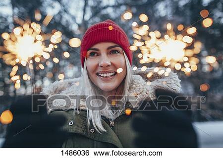 Happy woman holding sparklers during winter View Large Photo Image Stock Photograph - Happy woman holding sparklers during winter. Fotosearch