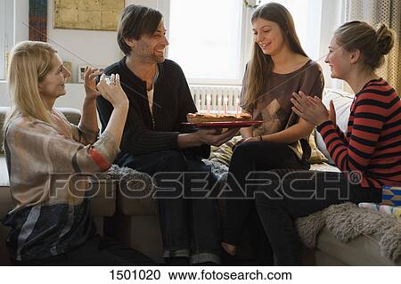 Happy woman looking at family with birthday cake in living room View Large Photo Image Stock Image - Happy woman looking at family with birthday cake in living room. Fotosearch