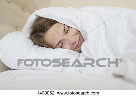 Stock Image - Happy woman sleeping in bed at home. Fotosearch