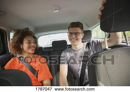 Happy young couple riding in back seat of car View Large Photo Image Stock Photo - Happy young couple riding in back seat of car. Fotosearch