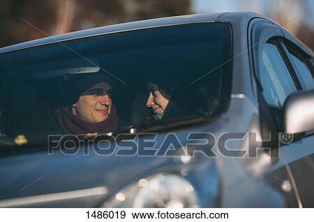 Happy young couple romancing in car View Large Photo Image Stock Photo - Happy young couple romancing in car. Fotosearch