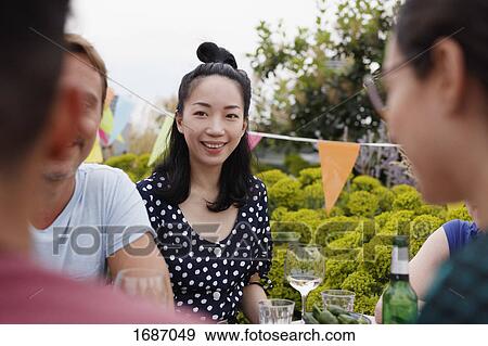 Happy young woman sitting with friends on patio View Large Photo Image Stock Photo - Happy young woman sitting with friends on patio. Fotosearch