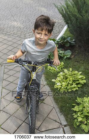 High angle portrait of boy riding bicycle on street by plants View Large Photo Image Stock Photo - High angle portrait of boy riding bicycle on street by plants. Fotosearch