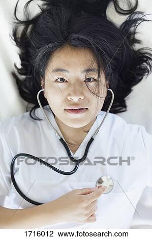 High angle portrait of female doctor listening to self heart beat with stethoscope View Large Photo Image Stock Image - High angle portrait of female doctor listening to self heart beat with stethoscope. Fotosearch